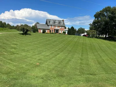 Mowed hillside lawn in front of a brick house