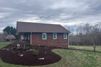 Fresh mulch beds with small plantings beside a cedar-sided house