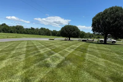 Freshly mowed lawn with stripes and a truck and trailer nearby