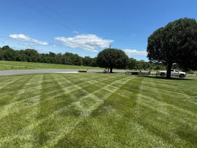 Wide striped lawn with a truck and trailer nearby